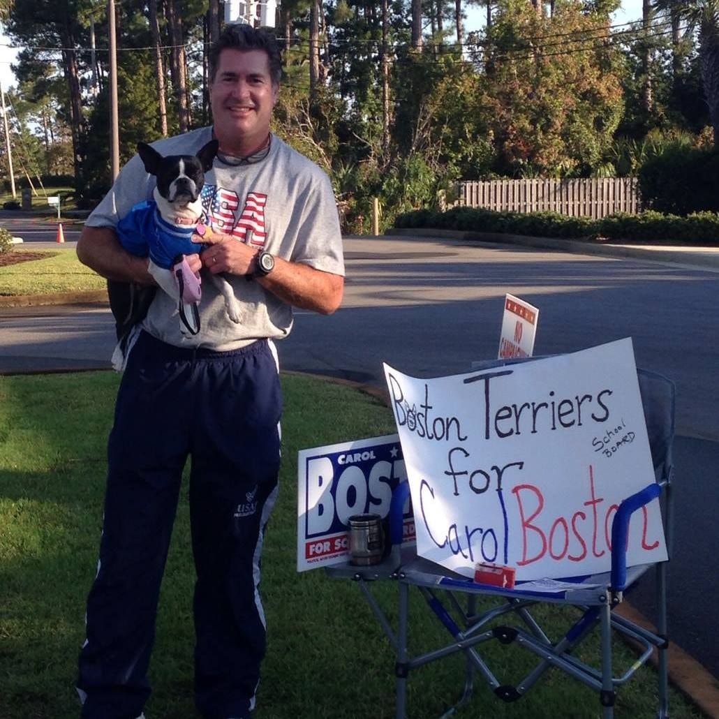 Man holding a Boston Terrier next to a Boston Terriers for Carol handmade sign