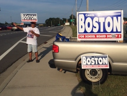 Supporter waving next to a truck with Carol Boston campaign signs